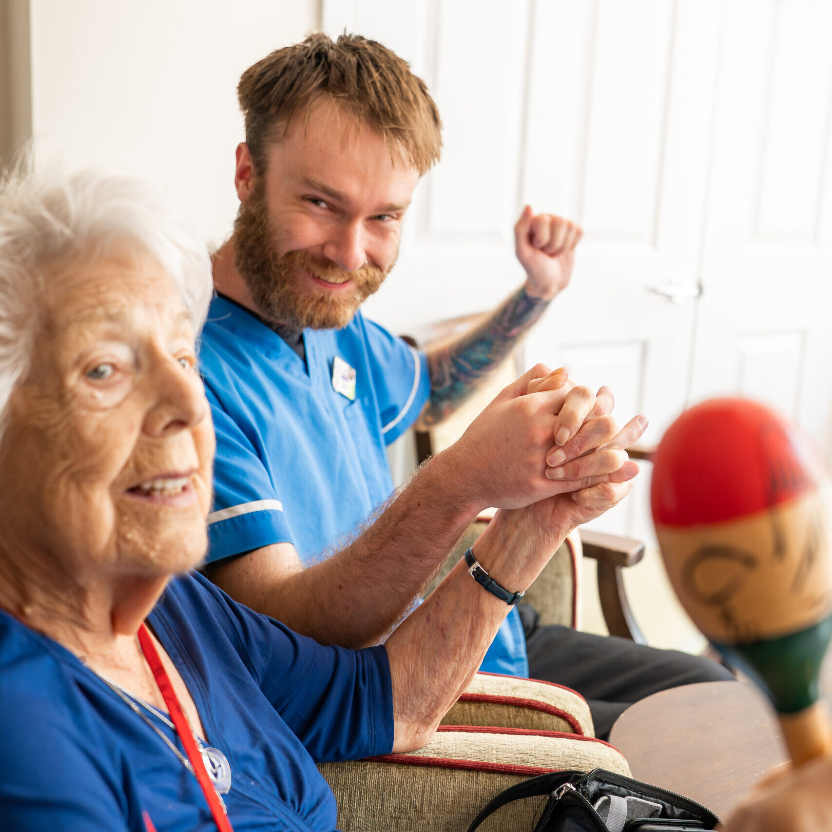 Visiting entertainer playing maracas with a resident at Tudor Lodge