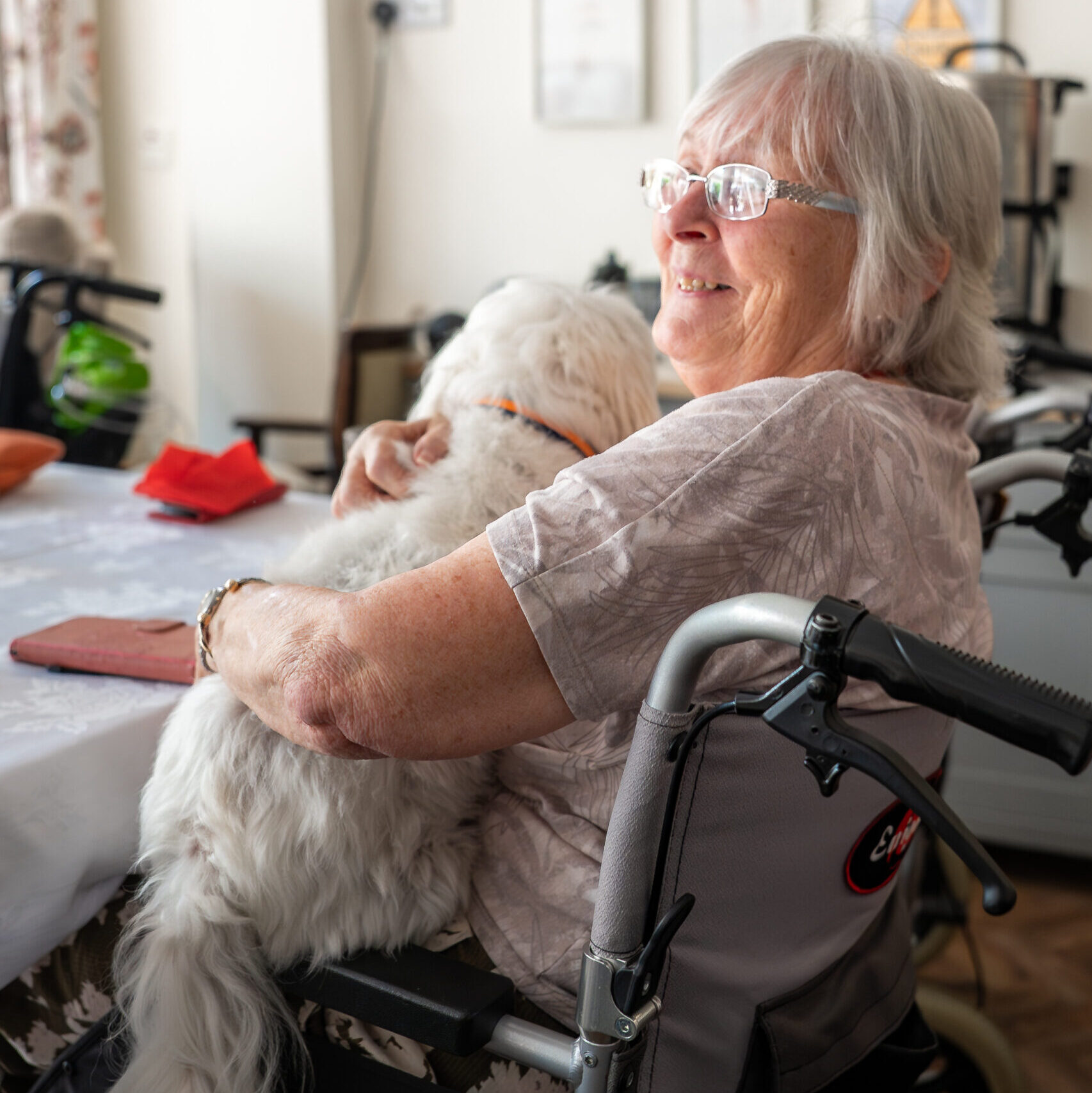 Resident cuddling a small white dog at Tudor Lodge