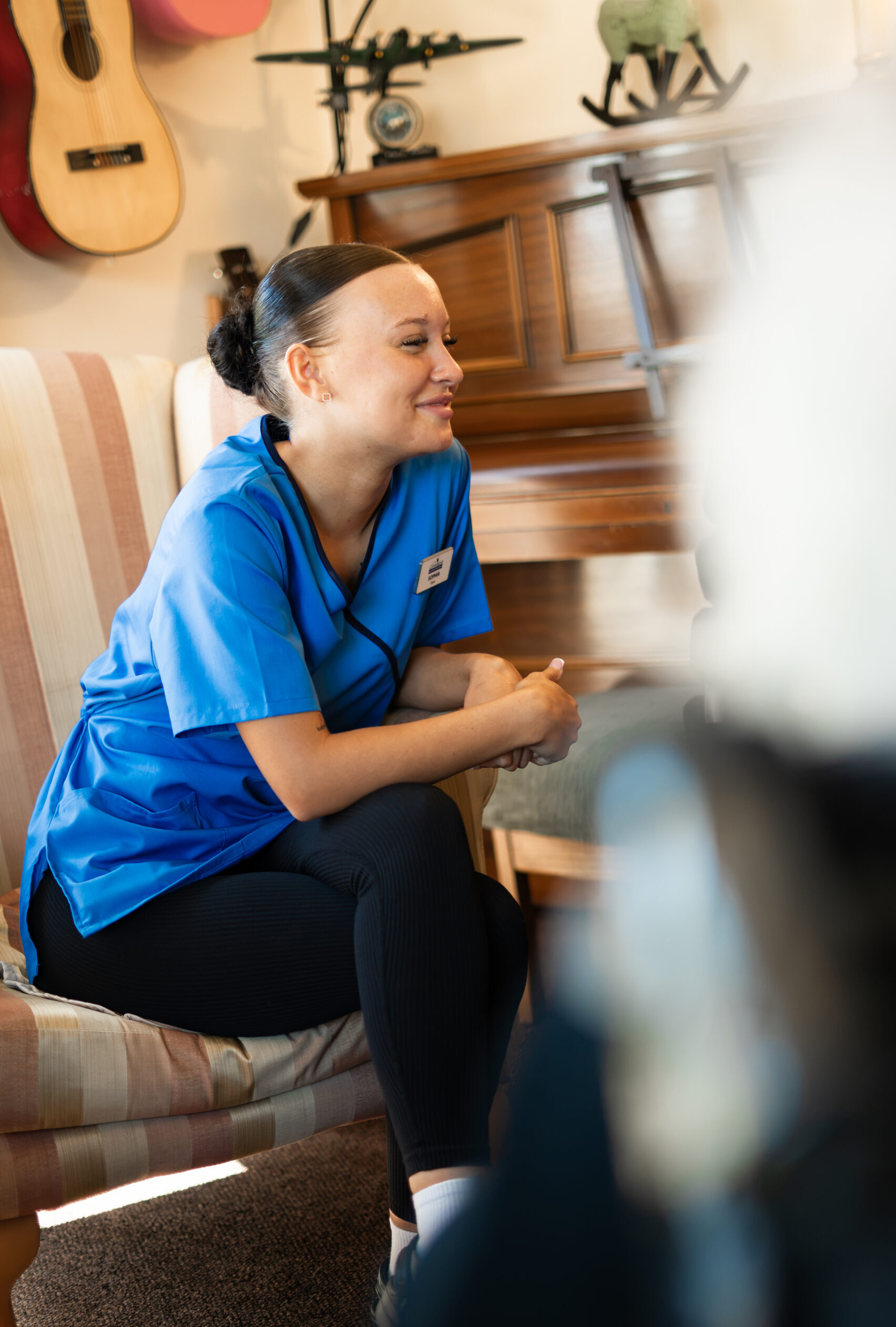 Carer in a blue uniform talking with a resident at Canford Manor
