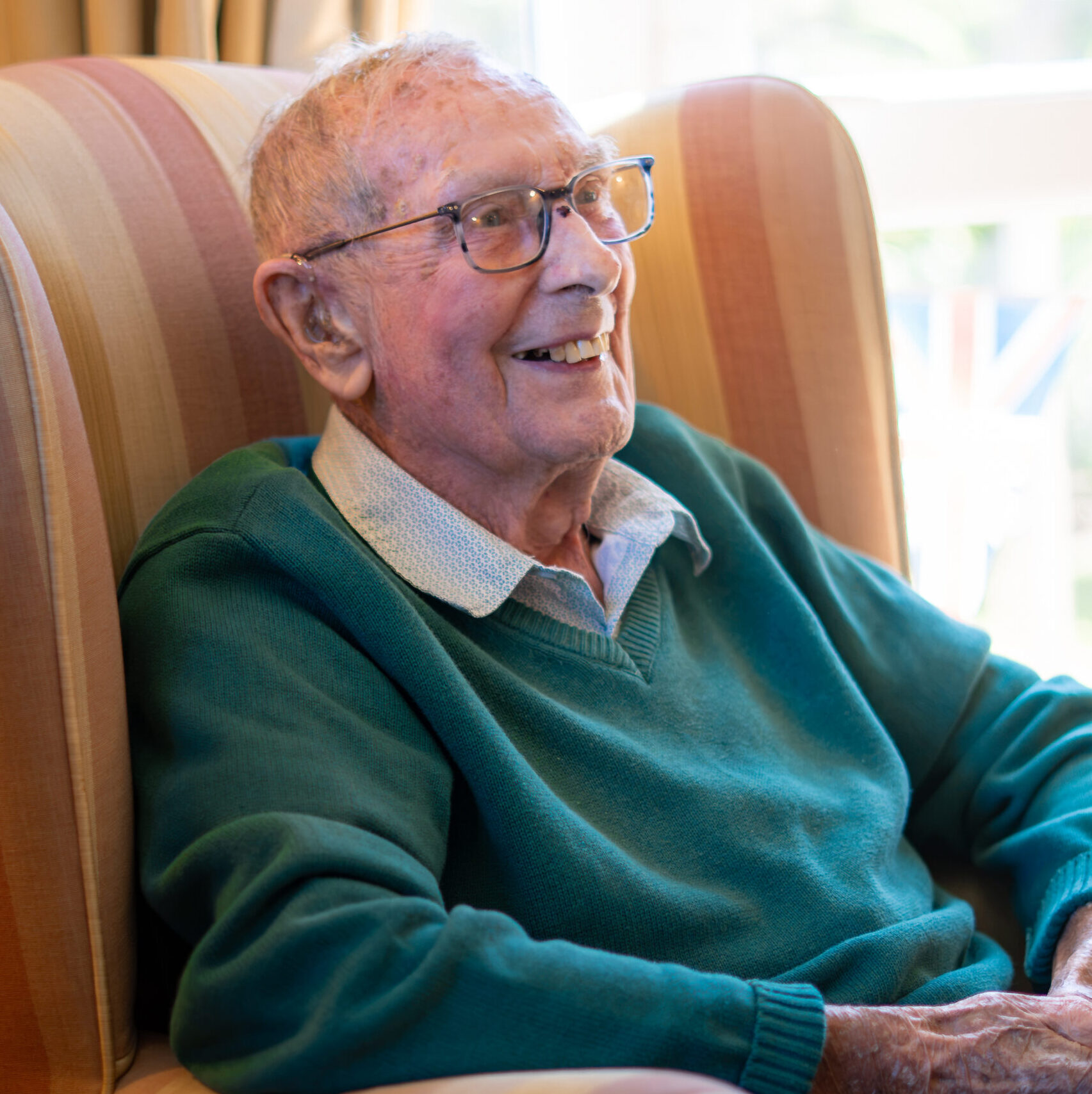 Smiling resident in a green jumper at Canford Manor