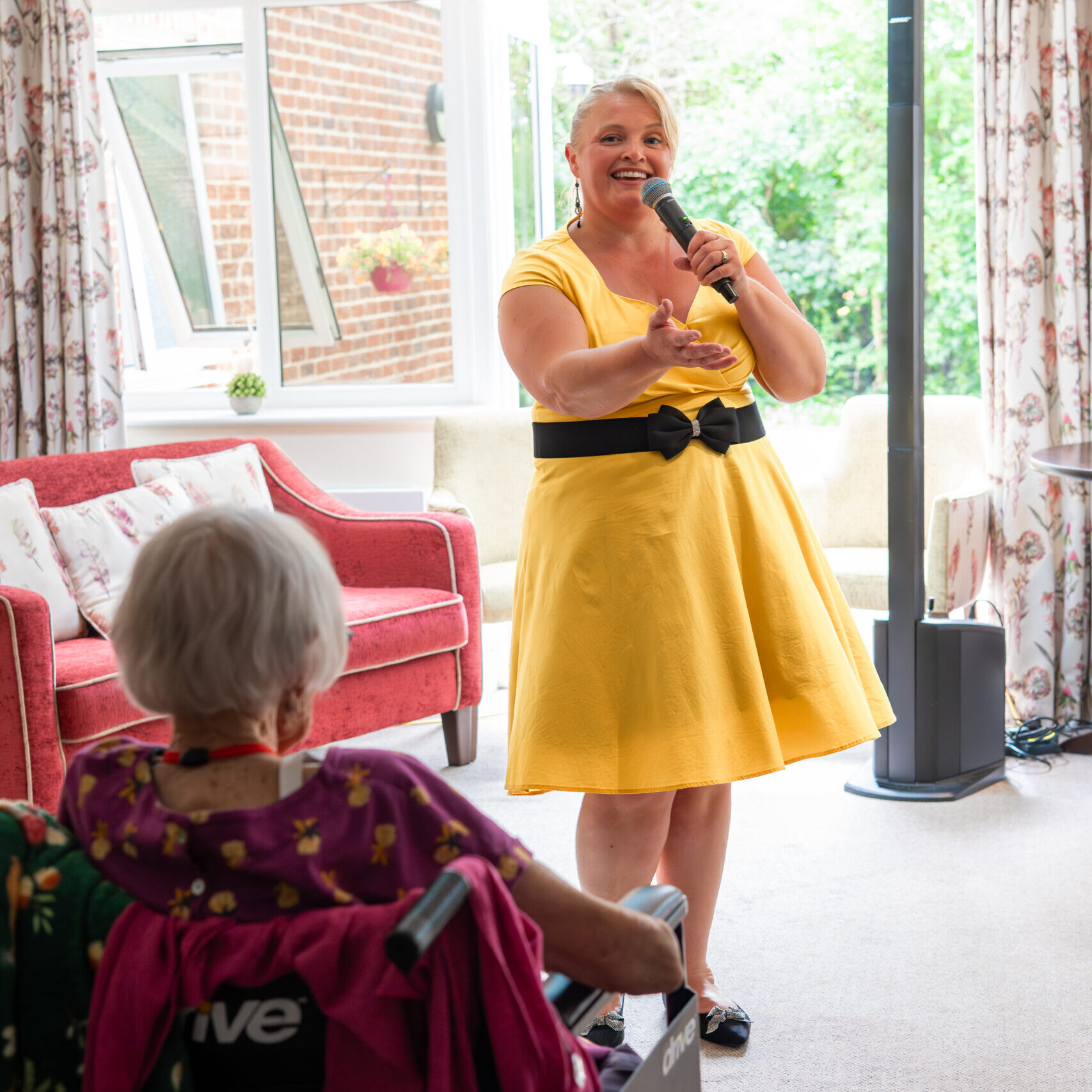 Singer in a yellow dress performing for residents at Tudor Lodge